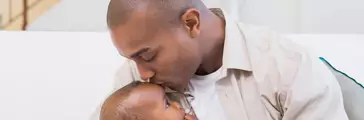 Happy father spending time with baby on the couch
